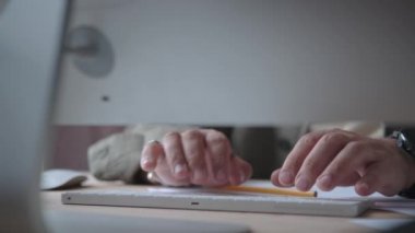 Erkek işadamı çalışıyor, masada oturuyor, klavyede yazı yazıyor.