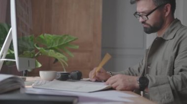 Ofiste belgelerle çalışan ve kahve içen bir adam.