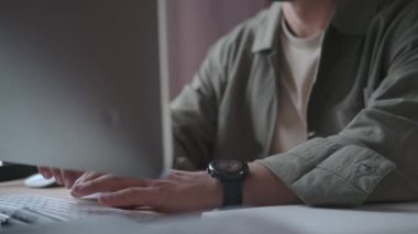 35 yaşında, gözlüklü ve sakallı bir adam bilgisayarın başına oturur ve çalışır.