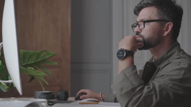 Hombre serio con gafas trabajando en la oficina delante de la computadora — Vídeos de Stock