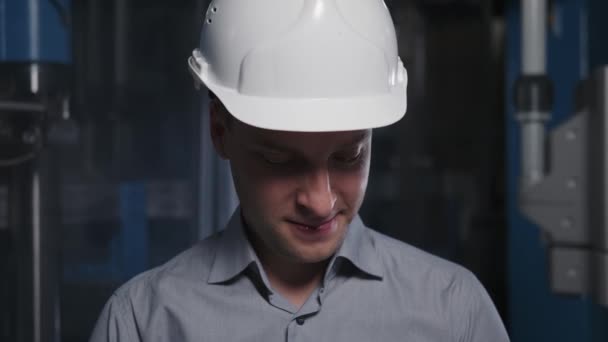 Positive top manager raises head, lsmiles and adjusts his helmet. — Stock Video