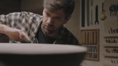 Marangoz, tahta bir masanın yüzeyinin pürüzsüzlüğünü kontrol eder..