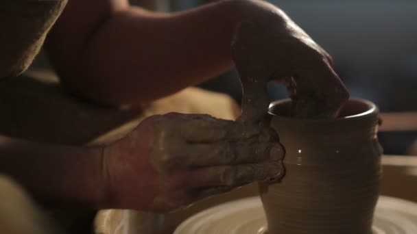 Handen van een pottenbakker, het creëren van een aarden pot op de cirkel — Stockvideo