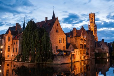 Buildings on canal at night in Bruges, Belgium clipart
