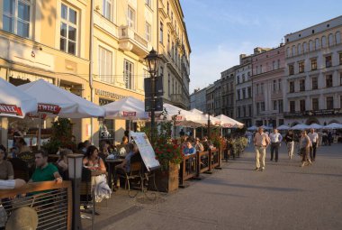 Krakow / Polonya / 30 Haziran 2010: Eski pazar meydanı bir yaz akşamı asfalt kafelerle kaplandı. İnsanlar öğleden sonra güneşinde içki içerek rahatlar..