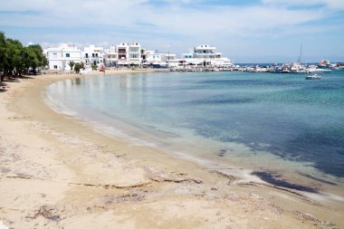 Piso Livadhi, Paros, Yunanistan. Korunaklı mavi suyu olan plaj ve deniz manzarası. Huzur manzarası, arka planda küçük bir liman olan sessiz bir koy. Temiz gökyüzü - Boşluğu kopyala.