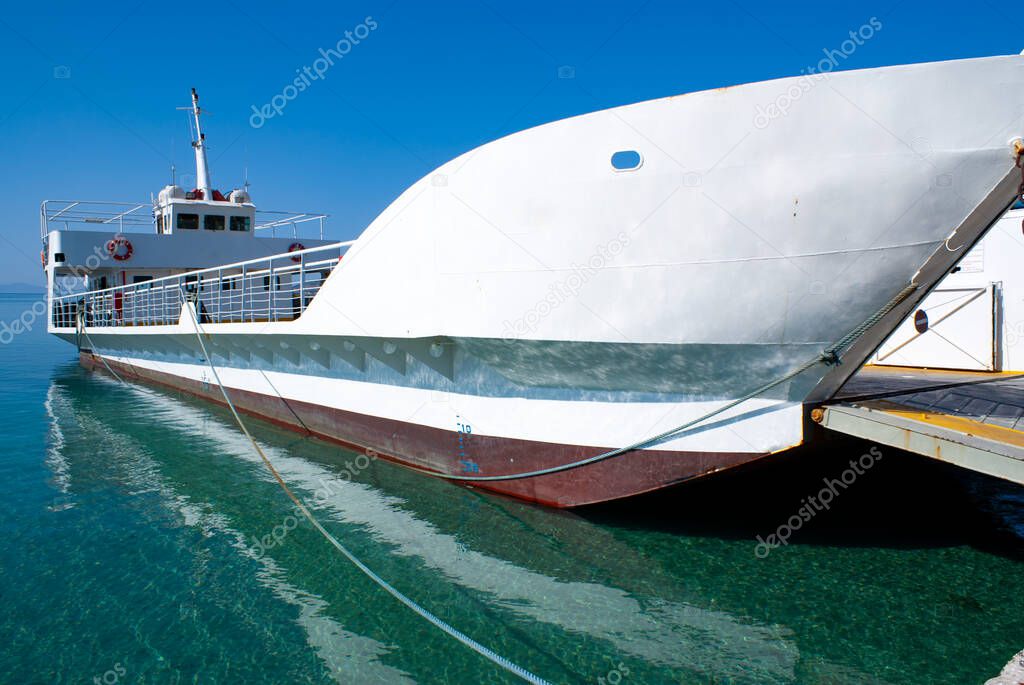 Greece, Antiparos island. Small ferry moored at harbor. Dramatic angular view of side of boat. Blue sky and copy space. Landscape aspect. Traditional landing craft type of vessel