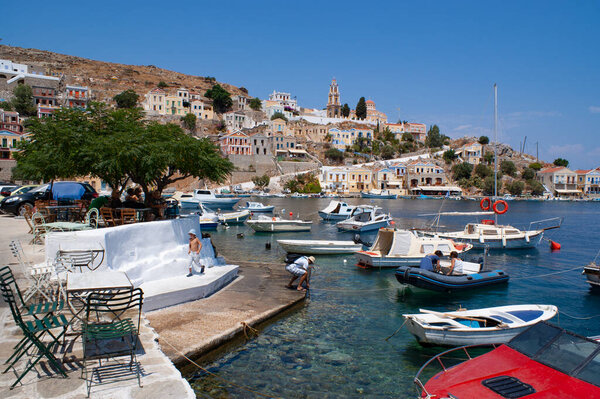 Symi - Greece - August 17 2009 : Charming small port with colorful pleasure boats moored Beautiful picturesque bay surrounded by neo classical buildings and cafes and bars