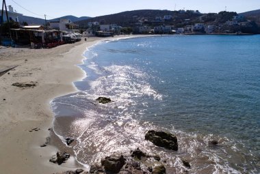 Pserimos Adası Yunanistan. Güzel kumlu sahil, kumlu sahilde süzülen yumuşak dalgalar üzerinde güneş parıldıyor. Koyu, mavi denizi ve tepeleri olan büyüleyici bir manzara. Boşluğu kopyala.