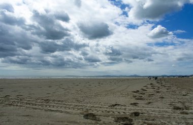 Black rock sands, Pothmadog, Wales.  Dramatic sky, pristine sandy beach. A bright summers day. Distant mountains of Snowdonia on the horizon. Welsh seaside landscape. Copy space
