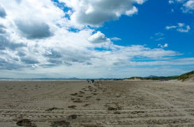 Siyah kaya kumları, Pothmadog, Galler. Bir yaz günü geniş kumlar üzerinde dramatik bir gökyüzü. Ufukta Snowdonia 'nın uzak dağları görünüyor. Galler deniz manzarası. Boşluğu kopyala