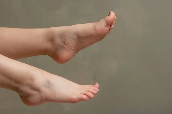 close-up close-up of Caucasian white woman\'s feet and soles on a greenish-gray wall background