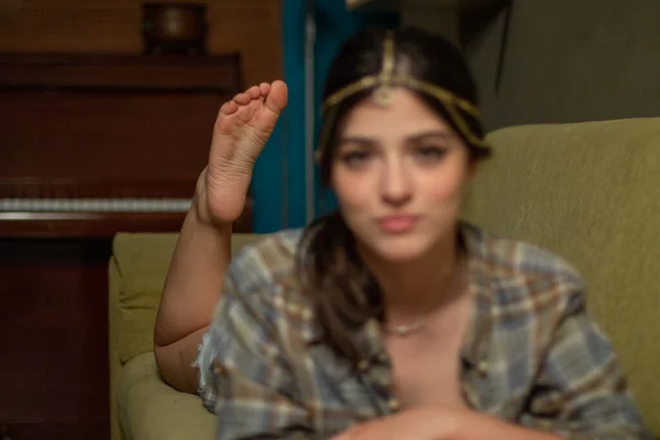 Focused barefoot sole of Caucasian girl lying on a green sofa at home. His face is out of focus