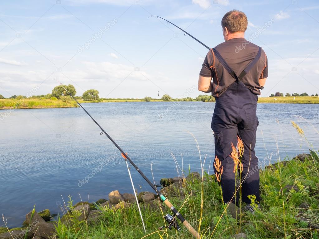 Male fisherman standing at the river in summer