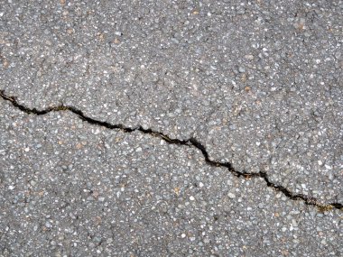 Siyah asfalttaki çapraz çatlağın yakın plan görüntüsü