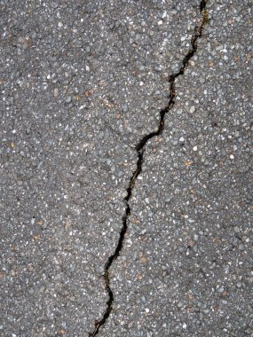 Siyah asfalttaki çapraz çatlağın yakın plan görüntüsü