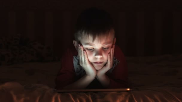 Niño viendo dibujos animados en la almohadilla táctil en la noche — Vídeo de stock