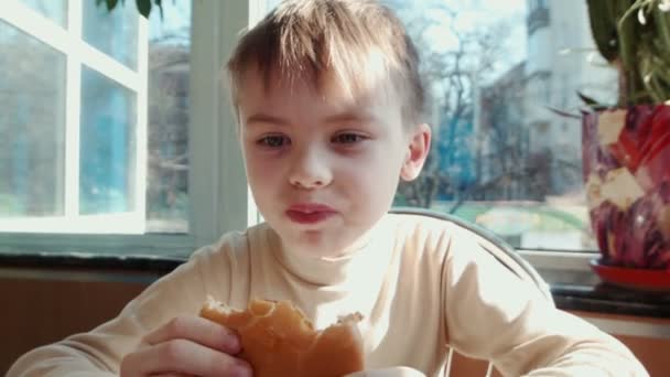 Chłopiec jedzenia hamburgera w restauracji typu fast food — Wideo stockowe