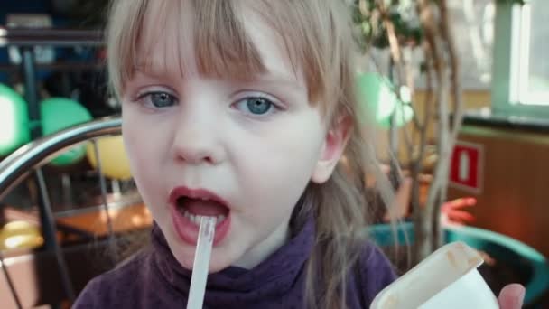 La petite fille boit un cocktail et lèche la sauce — Video