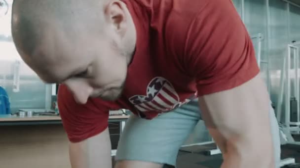 Спортсмен бодибилдер закрепляет штангу на штанге — стоковое видео