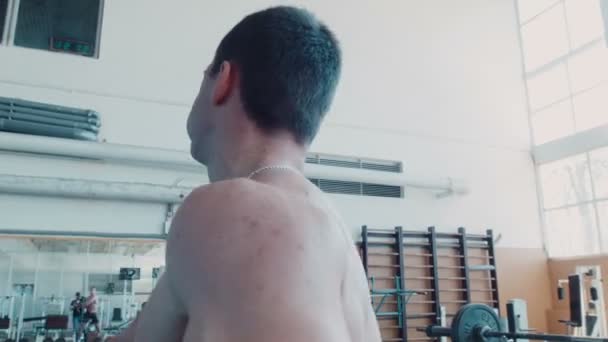 Bodybuilder macht rotierende Übung mit Langhantel — Stockvideo