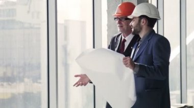Planı elinde bina ile konuşurken mimarlar