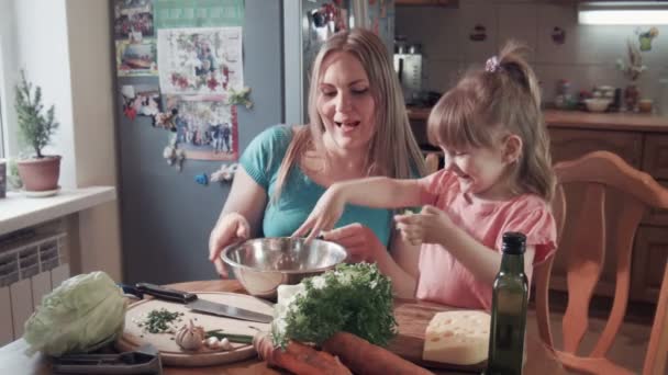 Девочка и мама разрывают салат в миске — стоковое видео