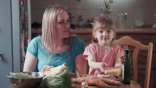 Little girl and her mother biting cheese with holes — Stock Video