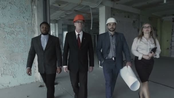 Team of builders in suits, hard hat, move, look directly into camera. Black man, aged engineer — Stock Video