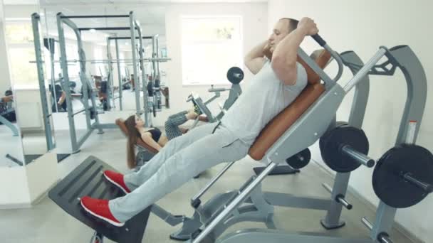 Man doen squats in kappen machine terwijl vrouw doen beenpres — Stockvideo