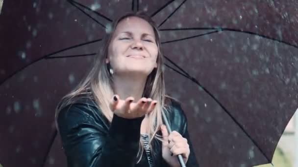 Mulher loira desfrutando de chuva sob guarda-chuva preto torção — Vídeo de Stock