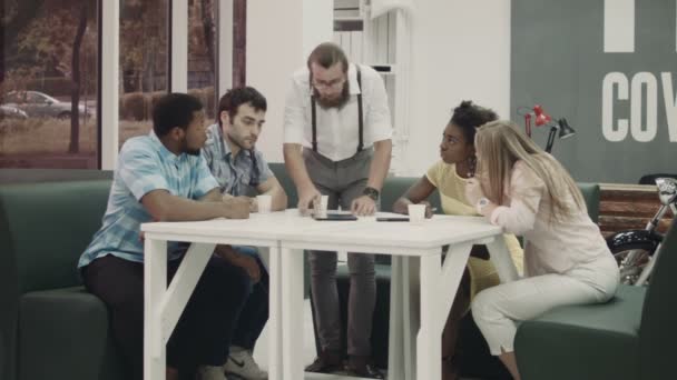 Homens discutindo informações sobre tablet, enquanto as mulheres escrevendo algo para baixo — Vídeo de Stock