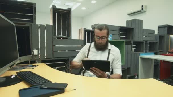 Trabajador barbudo usando tableta y divertirse en el lugar de trabajo — Vídeo de stock