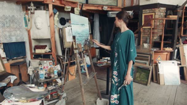 Kvinnan konstnär står framför målningen i studio — Stockvideo