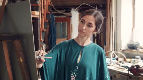Portrait of young woman painting a canvas in a studio — Stock Video