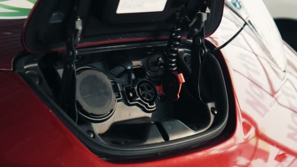 Красный электромобиль крупным планом на точке зарядки — стоковое видео