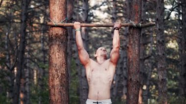 Yakışıklı vücut geliştirmeci pull-up ormandaki yapıyor