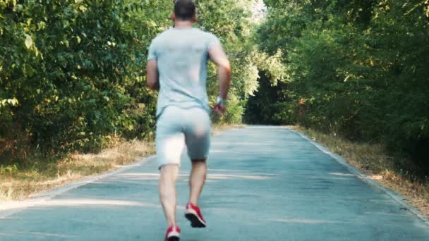 Vista trasera del joven corriendo rápido por el camino — Vídeo de stock