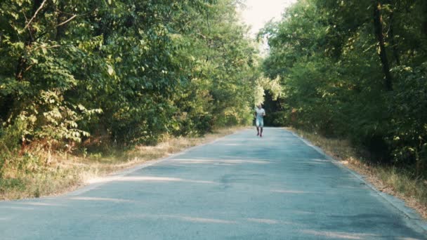 Homem correndo ao longo de uma estrada de floresta — Vídeo de Stock