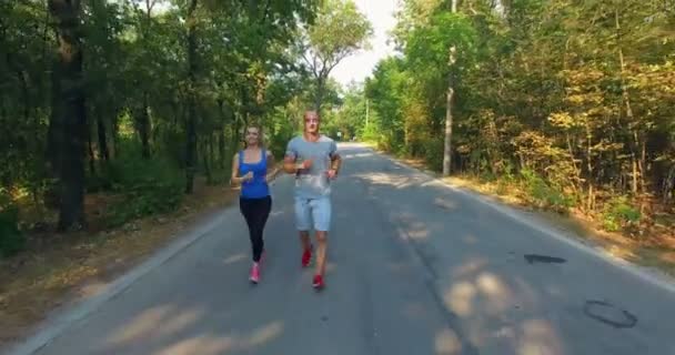 Casal correndo ao longo da estrada na floresta — Vídeo de Stock