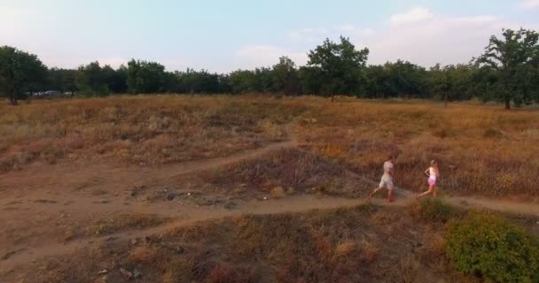 Paar joggen door grasland op een voetpad — Stockvideo