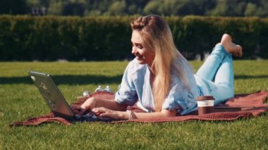 Genç kadınla çimenlerin üzerinde onu laptop ile rahatlatıcı