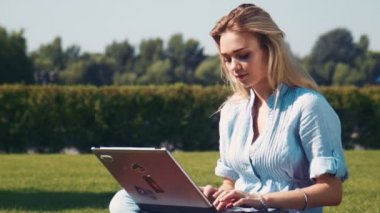 Dizüstü bilgisayarda yazarak ve kameraya bakarak genç sarışın kız