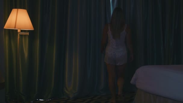 Blonde vrouw opent gordijnen in de slaapkamer — Stockvideo