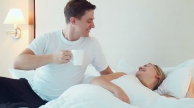 Adam yatakta uyuyan kadın için bir fincan çay ya da kahve getir