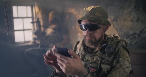 Militär man med hjälp av smartphone inne grungy byggnad — Stockvideo