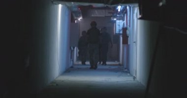 Profesyonel SWAT ekibi karanlık koridorda yürüyor.