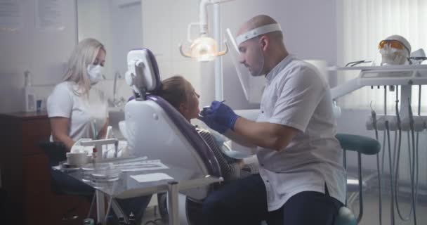 व्यावसायिक दंतचिकित्सक किशोर मुलीचे दात बरे — स्टॉक व्हिडिओ