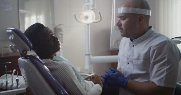 Dentista diverso e paciente discutindo o tratamento — Vídeo de Stock