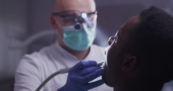 Fokuserade tandläkare som behandlar tänder hos patienten — Stockvideo